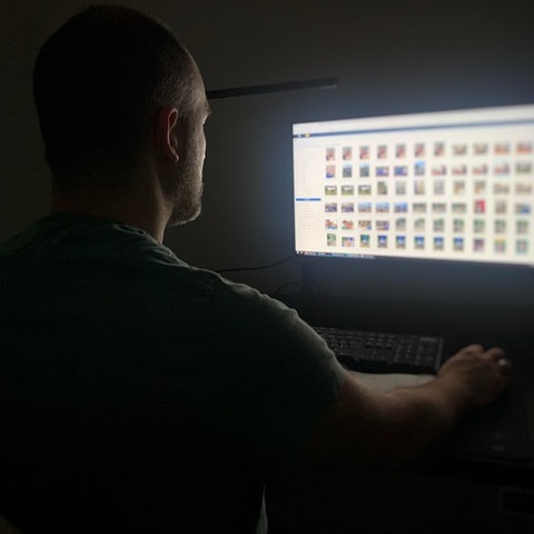 Symbolbild: Ein Mann vor einem Computer im Dunkeln.