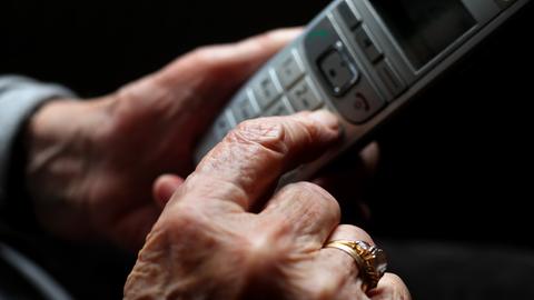 Hände einer älteren Frau halten einen Telefonhörer (Sujetbild)