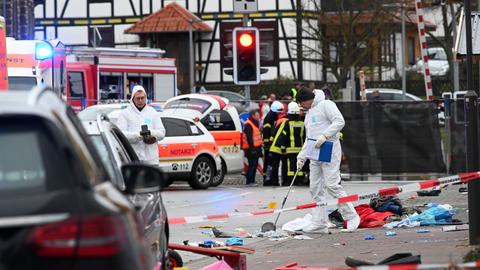 Einsatzkräfte in weißen Overalls nehmen an der Unfallstelle Spuren auf.  