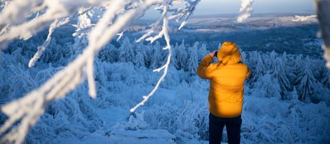 Spaziergänger auf dem Großen Feldberg im Taunus, der ein Foto von der schneebedeckten Umgebung macht
