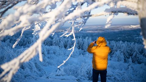 Spaziergänger auf dem Großen Feldberg im Taunus, der ein Foto von der schneebedeckten Umgebung macht