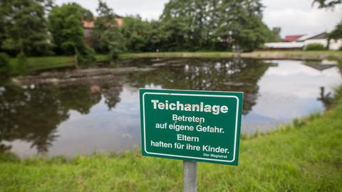 Schild mit der Aufschrift "Eltern haften für ihre Kinder" an der Teichanlage.