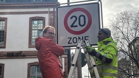 Verkehrsdezernent Wolfgang Siefert (Grüne) (r.) hängt das erste Tempo-20-Schild in der Innenstadt in Frankfurt auf.