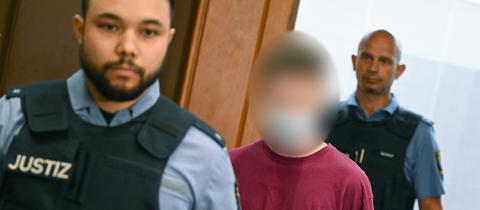 Der Angeklagte Marvin E. betritt in Begleitung von Justizbeamten den Gerichtssaal des Frankfurter Oberlandesgerichts.