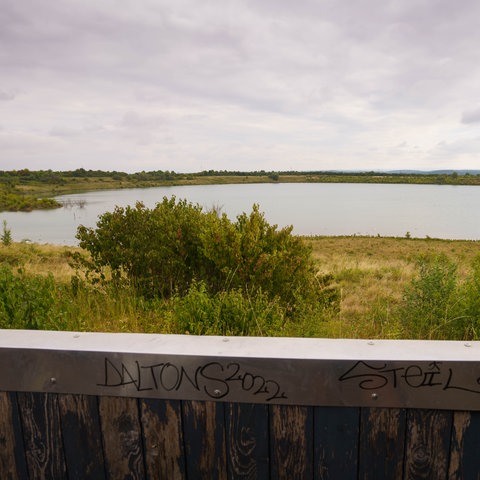 Teufelsee, im Vordergrund die Brüstung eines Holzhäuschens 