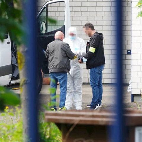 Drei Ermittler am Tatort, einer trägt einen weißen Schutzanzug