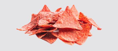 Rote Tortilla-Chips vor hellgrauem Hintergrund.
