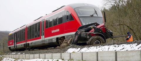 Zu sehen ist das Fahrerhaus eines Regionalzuges, vorne daran klemmt ein kleiner Traktor