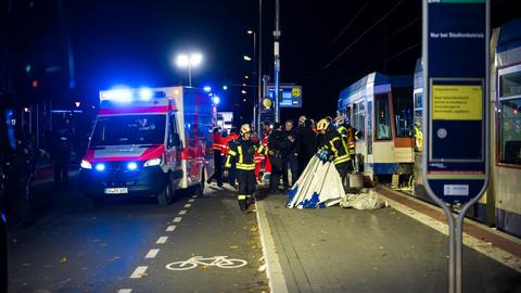 Einsatzkräfte von Polizei und Feuerwehr stehen im Dunkeln neben einer Straßenbahn.