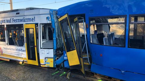 Zwei kollidierte Straßenbahnen mit gesplitterten Fenstern und herausgebrochenen Türen stehen ineinander verkeilt.