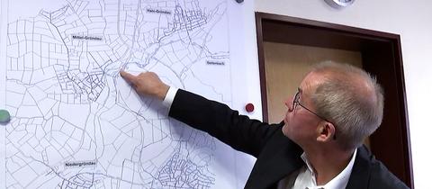 Gründaus Bürgermeister Gerald Helfrich zeigt das Wassernetz auf einer Karte.