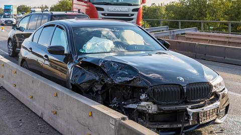Ein verunfalltes Auto mit eingedrücktem Kotflügel an einer Leitplanke auf der Autobahn stehend.