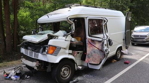 Ein beschädigter weißer Transporter steht nach einem Unfall auf einer Straße.