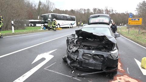 Ein schwer beschädigtes Auto und eine beschädigter Reisebus stehen nach einem Unfall auf einer Landstraße zwischen Aschaffenburg und Seligenstadt, dazwischen Einsatzkräfte
