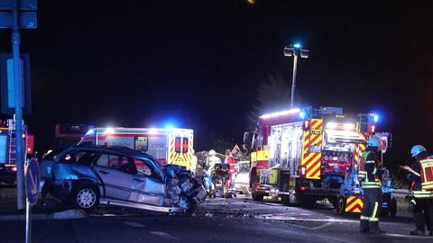 Rettungskräfte an der Unfallstelle neben einem zerbeulten Auto