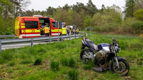 Verunglücktes Motorrad auf Grünstreifen, dahinter Rettungskräfte