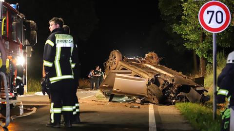 Ein Auto liegt nach einem Unfall auf einer Landstraße auf dem Dach.