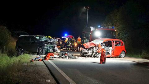 Zwei schwer beschädigte Autos und Einsatzkräfte nachts auf einer Landstraße