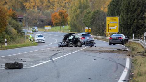 Auf einer Landstraße stehen zwei verunglückte Autos: Eine graue Mercedes A-Klasse, die an der linken Seite schwer getroffen wurde und ein schwarzer Audi in der Leitplanke.