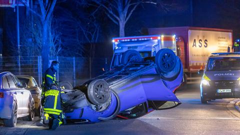 Ein Auto liegt auf dem Dach, daneben zwei beschädigte geparkte Autos.