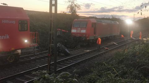 Einsatzkräfte stehen bei Sonnenaufgang an den Gleisen, dort stehen ein Traktor und ein Bahnwaggon