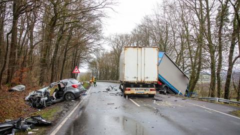 Zwei Lastwagen und ein schwer beschädigtes Auto an einer Straße