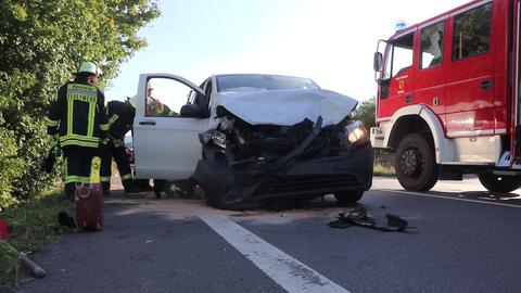 Die Feuerwehr steht neben einem Unfallauto auf der Landstraße