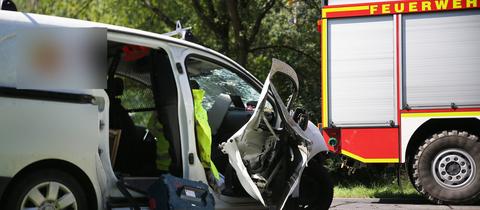 Beschädigtes Auto neben einem Feuerwehrauto