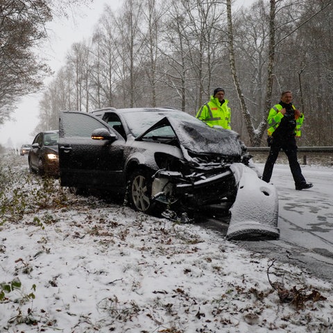 Nach einem Unfall parken Autos am Rand einer verschneiten Straße.