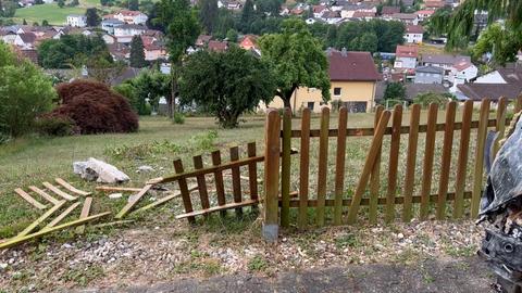 Unfallort in Wald-Michelbach - ein Zaun vor einem Abhang und am Ende ein Haus - das Loch in der Wand ist bereits notdürftig geflickt, 