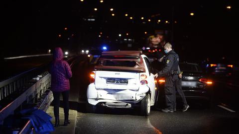 Zwei Polizisten untersuchen zwei Unfallautos, die auf einer Straße im Dunkeln nebeneinander stehen.