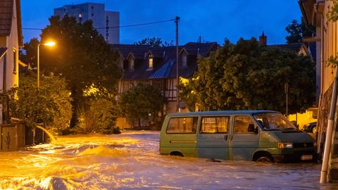 Wasser fließt durch eine Straße, Kleinbus steht im Wasser