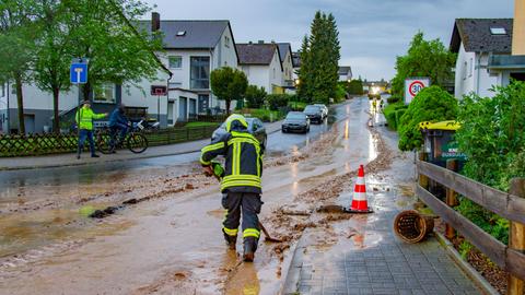 Ein Feuerwehrmann fegt Schlamm von der Straße.