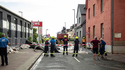 Feuerwehrleute sichern eine Straße ab, auf der Trümmerteile liegen