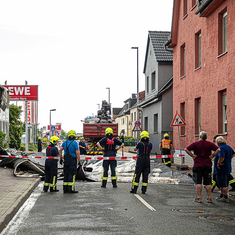 Feuerwehrleute sichern eine Straße ab, auf der Trümmerteile liegen