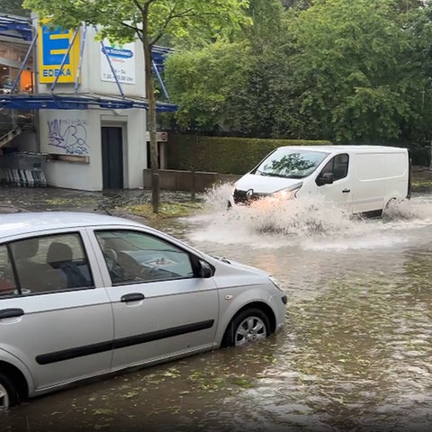 Autos in Kassel fahren auf überfluteter Straße