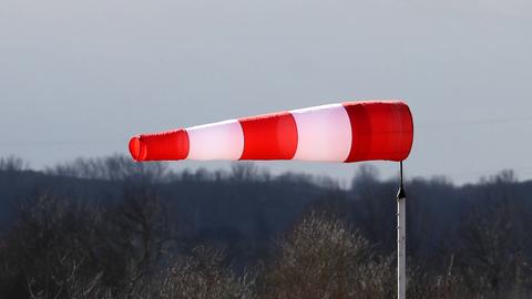 Foto eines rot-weiß gestreiften Windsackes, der aufgrundes des starken Sturmes waagerecht im Wind weht.