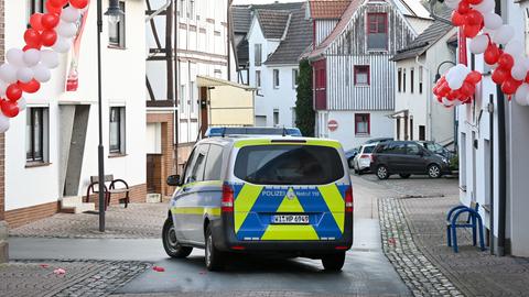 Ein Polizeiauto steht in einer Straße, die mit rot-weißen Luftballons und einem Banner geschmückt ist.