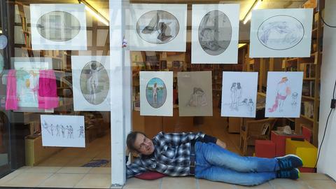 Künstler Achim Gogler liegt im Schaufenster der Wächtersbacher Buchhandlung "Dichtung & Wahrheit", die mit Goglers Aktgemälden zur Verkehrsberuhigung beiträgt.