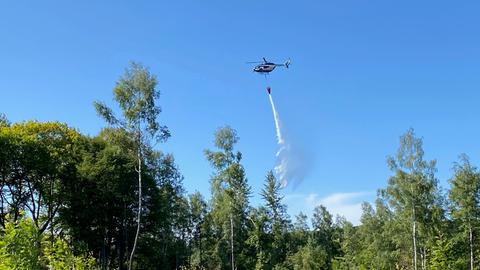 Hubschrauber wirft Löschwasser über Waldgebiet in Kassel ab