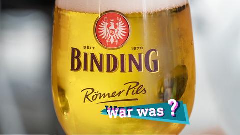 Nahaufnahme eines gefüllten Bierglases mit der Aufschrift "Binding - Römerpils" und einem Eintracht-Wappen darüber. Auf dem Bild eine kleine, farbige Grafik mit dem Schriftzug "war was?".