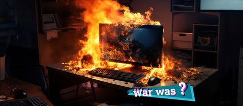 Foto von einem Computer in einem Büro, der in loderenden Flammen steht. Auf dem Foto eine kleine farbige Grafik mit dem Schriftzug "War was?". 