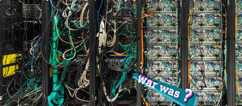 Foto eines Riesenrechners mit sehr vielen farbigen Kabeln. Auf dem Bild eine kleine, farbige Grafik mit dem Schriftzug "war was?".