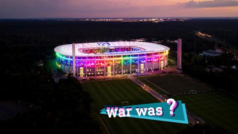 Foto vom Frankfurter WM-Stadion in der Abenddämmerung angestrahlt in Regenbogenfarben (Vogelperspektive). Auf dem Foto eine kleine farbige Grafik mit dem Schriftzug "War was?".