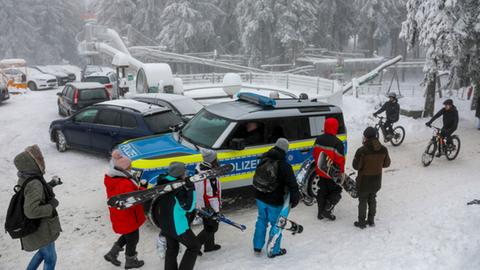 Wintersportler auf der schneebdeckten Wasserkuppe neben einem Polizeiauto