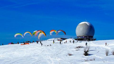 Gleitschirmflieger und Skifahrer auf den verschneiten Pisten an der Wasserkuppe