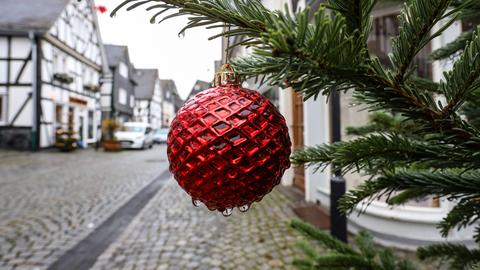 Rote Christbaumkugel groß im Bildvordergrund, dahiner Blick in eine Straße mit Fachwerkhäusern.