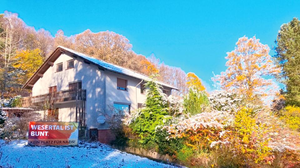 Einfamilienhaus in Alleinlage in der Landschaft. Davor steht ein Banner mit der Aufschrift "Wesertal ist bunt. Kein Platz für Nazis"