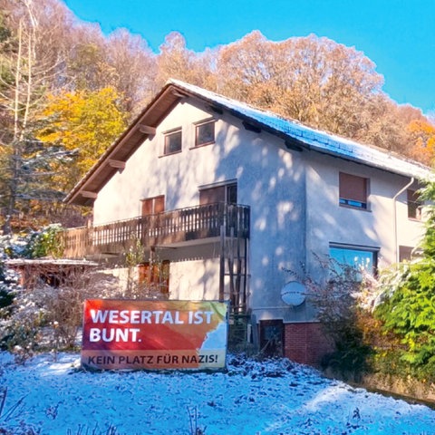 Einfamilienhaus in Alleinlage in der Landschaft. Davor steht ein Banner mit der Aufschrift "Wesertal ist bunt. Kein Platz für Nazis"