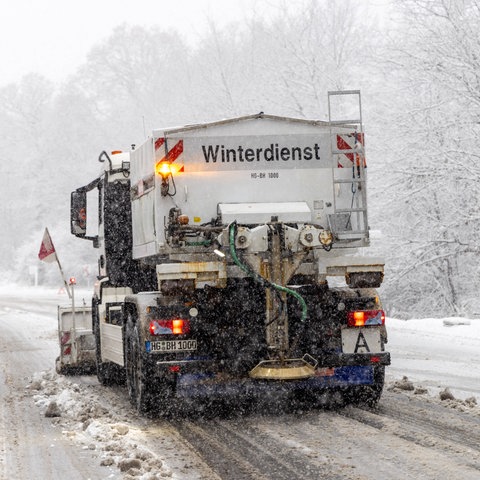Ein Räumfahrzeug des Winterdienstes fährt auf einer verschneiten Straße entlang.